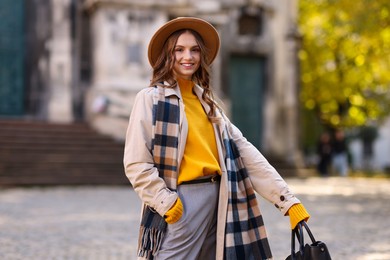 Photo of Charming young woman in stylish outfit on city street. Autumn season