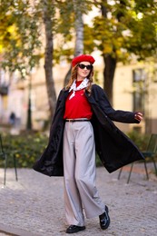 Photo of Charming young woman in stylish outfit on city street. Autumn season