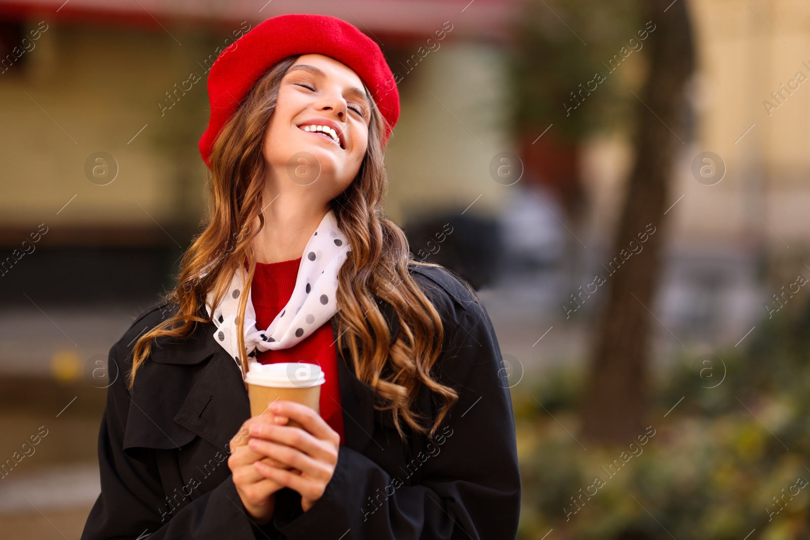 Photo of Stylish woman with cup of hot drink outdoors, space for text