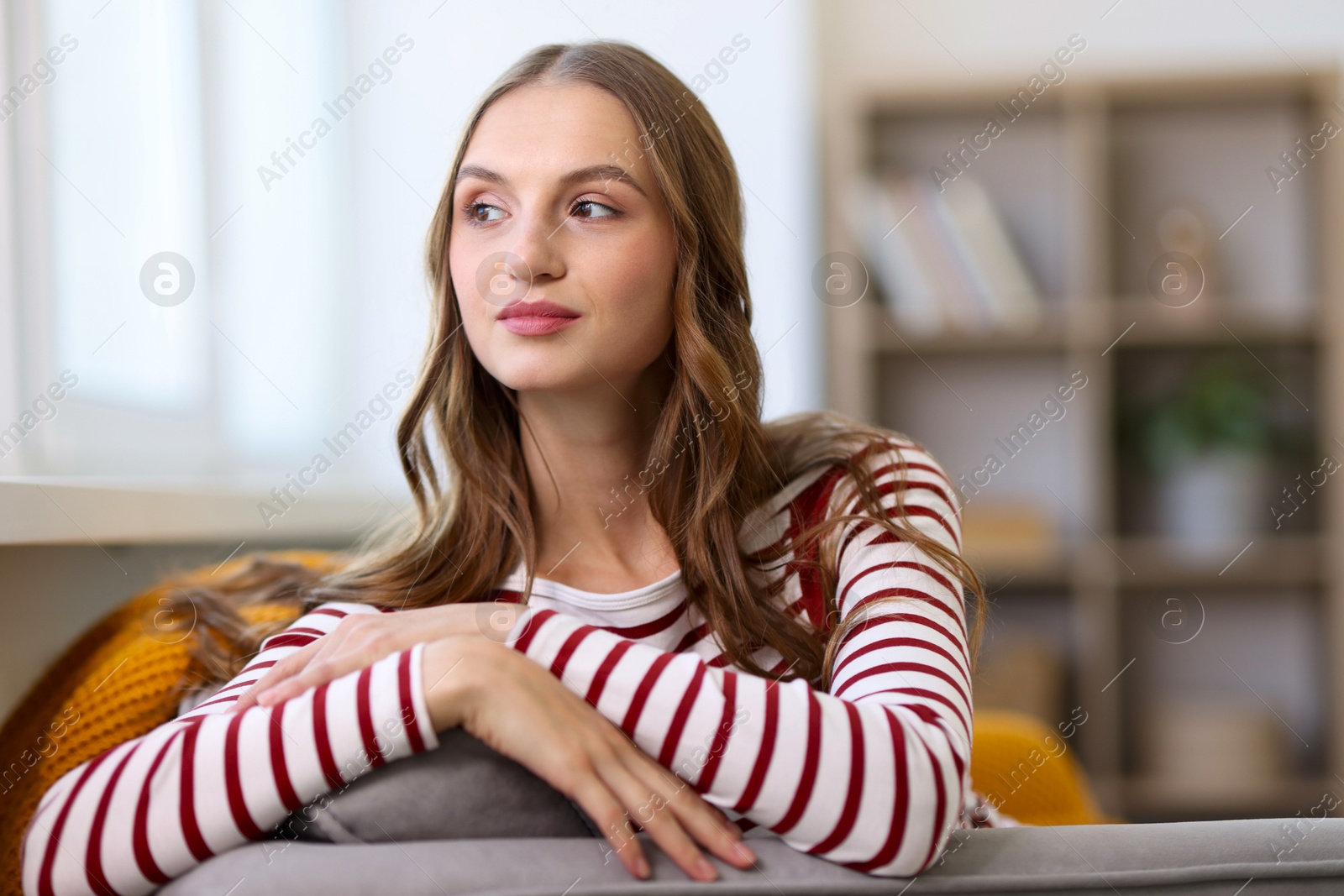 Photo of Charming young woman on sofa at home. Autumn atmosphere