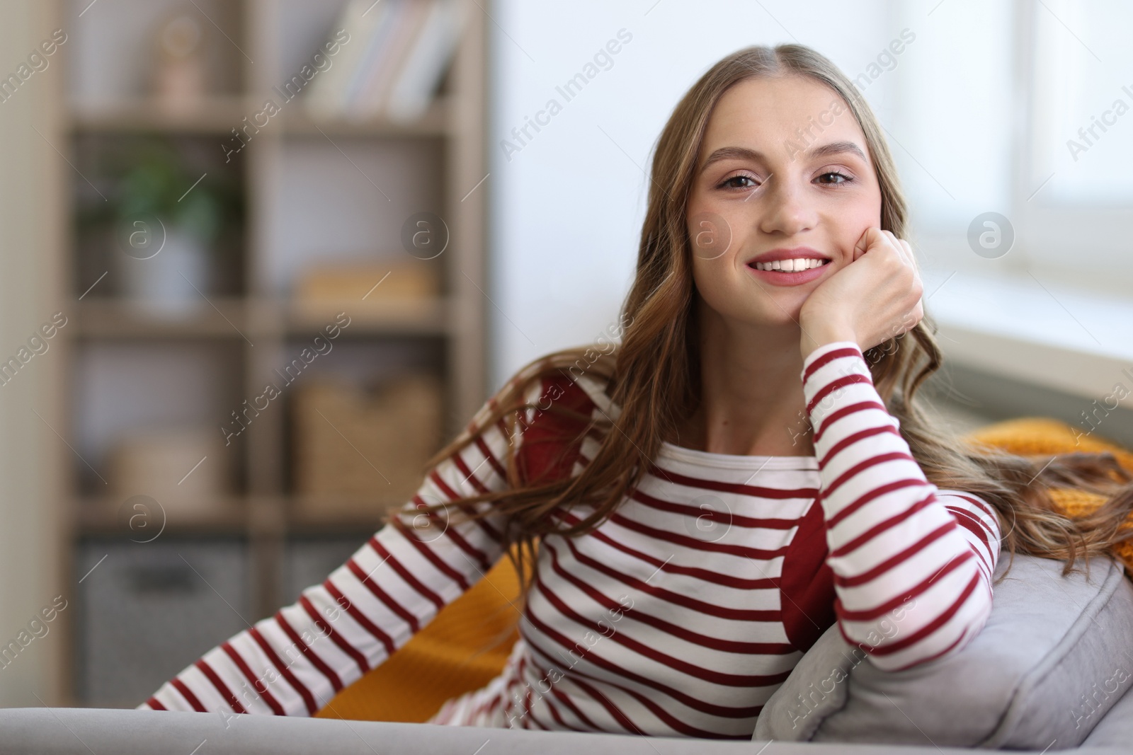 Photo of Charming young woman on sofa at home, space for text. Autumn atmosphere