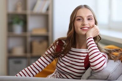 Photo of Charming young woman on sofa at home, space for text. Autumn atmosphere