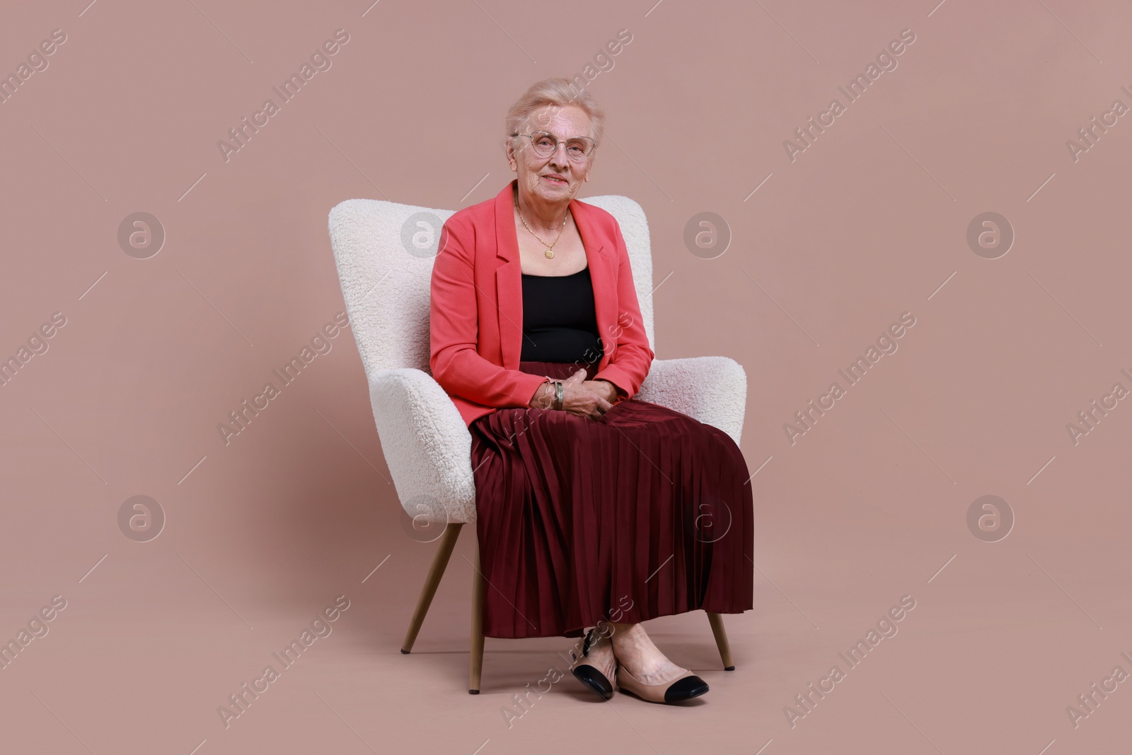 Photo of Senior woman in armchair on color background