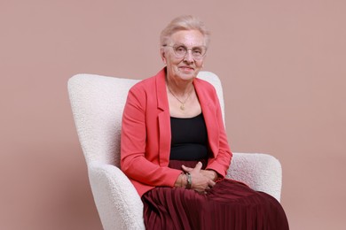 Photo of Senior woman in armchair on color background