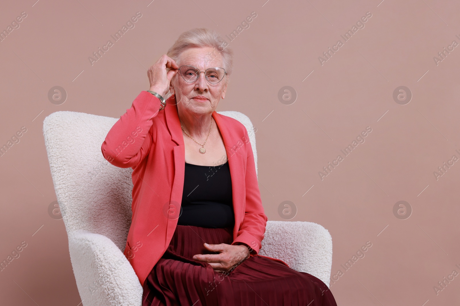 Photo of Senior woman in armchair on color background