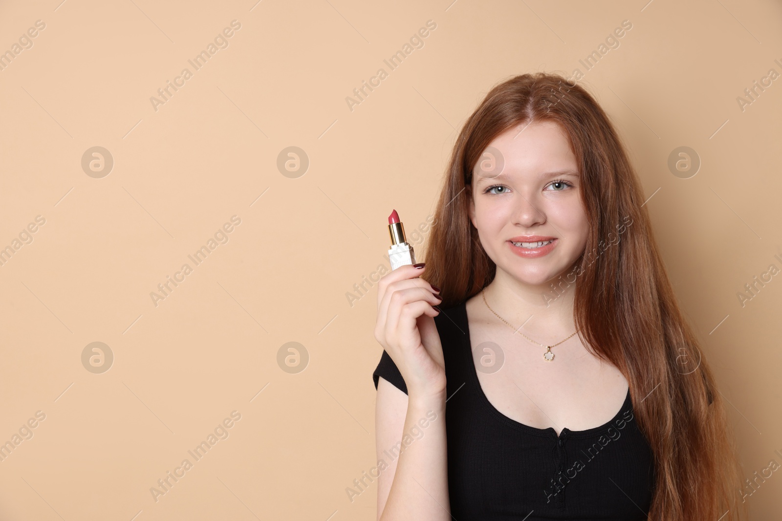 Photo of Smiling teenage girl with lipstick on beige background. Space for text