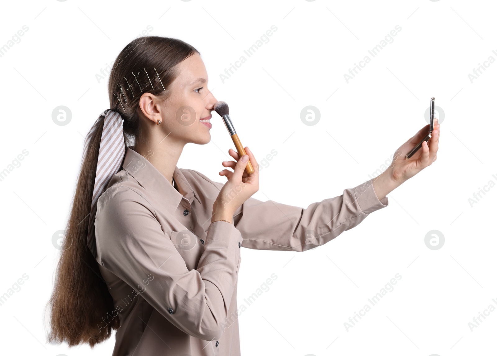 Photo of Smiling teenage girl applying blusher with makeup brush on white background