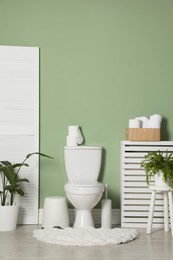 Photo of Folding screen, toilet bowl and houseplants in restroom