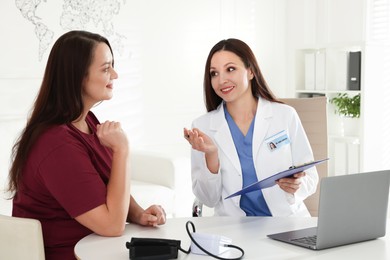 Photo of Overweight woman having consultation with nutritionist at desk in clinic