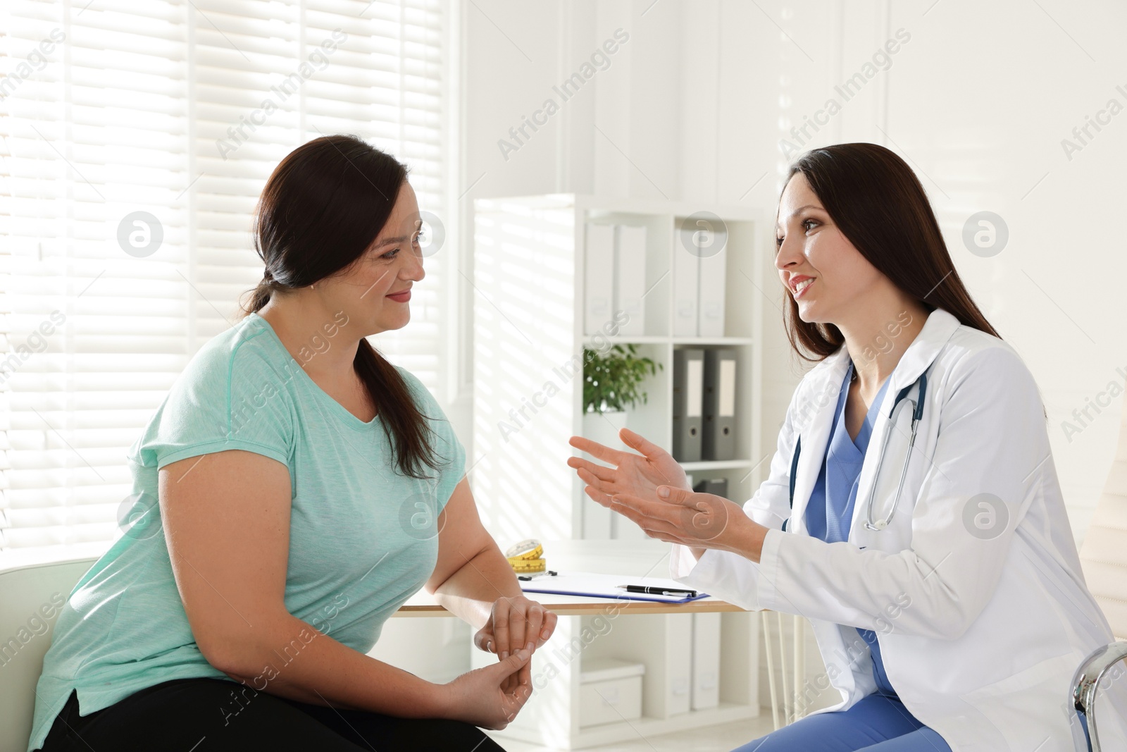 Photo of Nutritionist giving recommendations to overweight woman in hospital