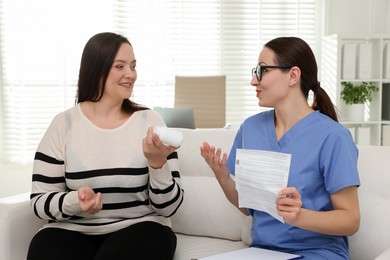 Photo of Nutritionist giving recommendations to overweight woman on couch in hospital