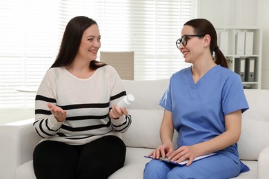 Photo of Nutritionist giving recommendations to overweight woman on couch in hospital