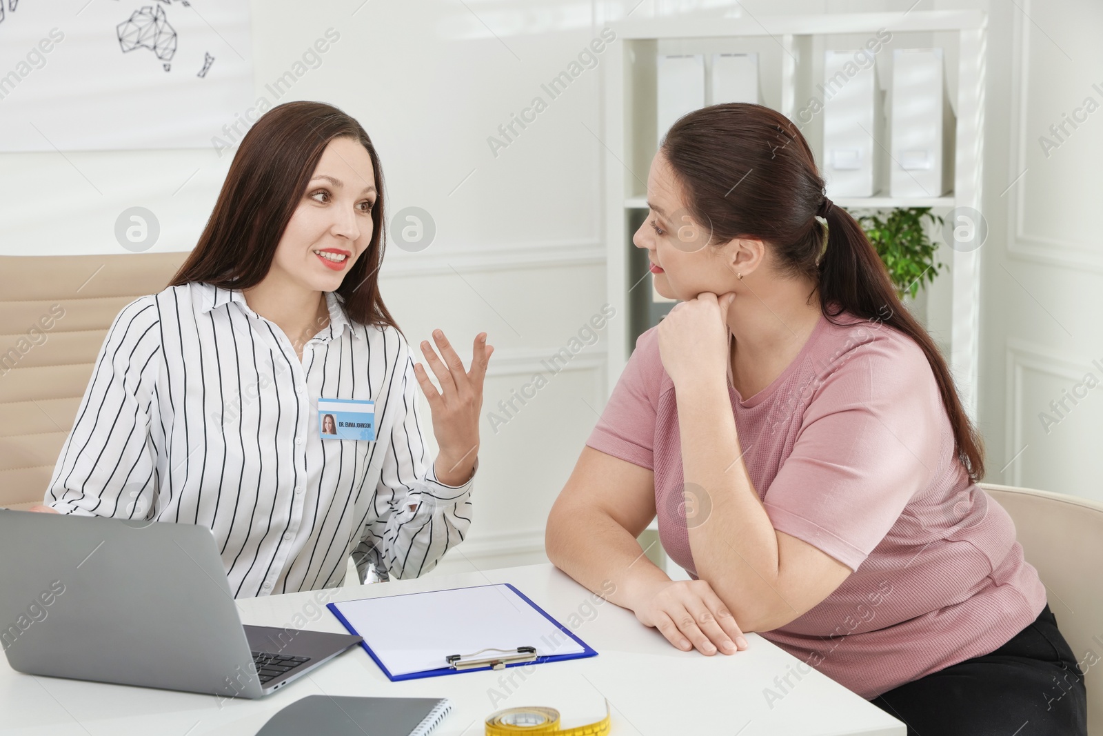 Photo of Overweight woman having consultation with nutritionist at desk in clinic