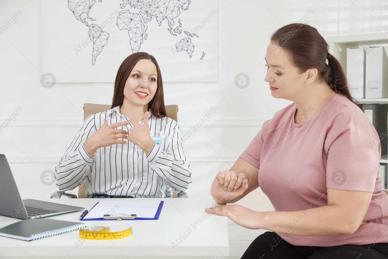 Photo of Overweight woman having consultation with nutritionist at desk in clinic