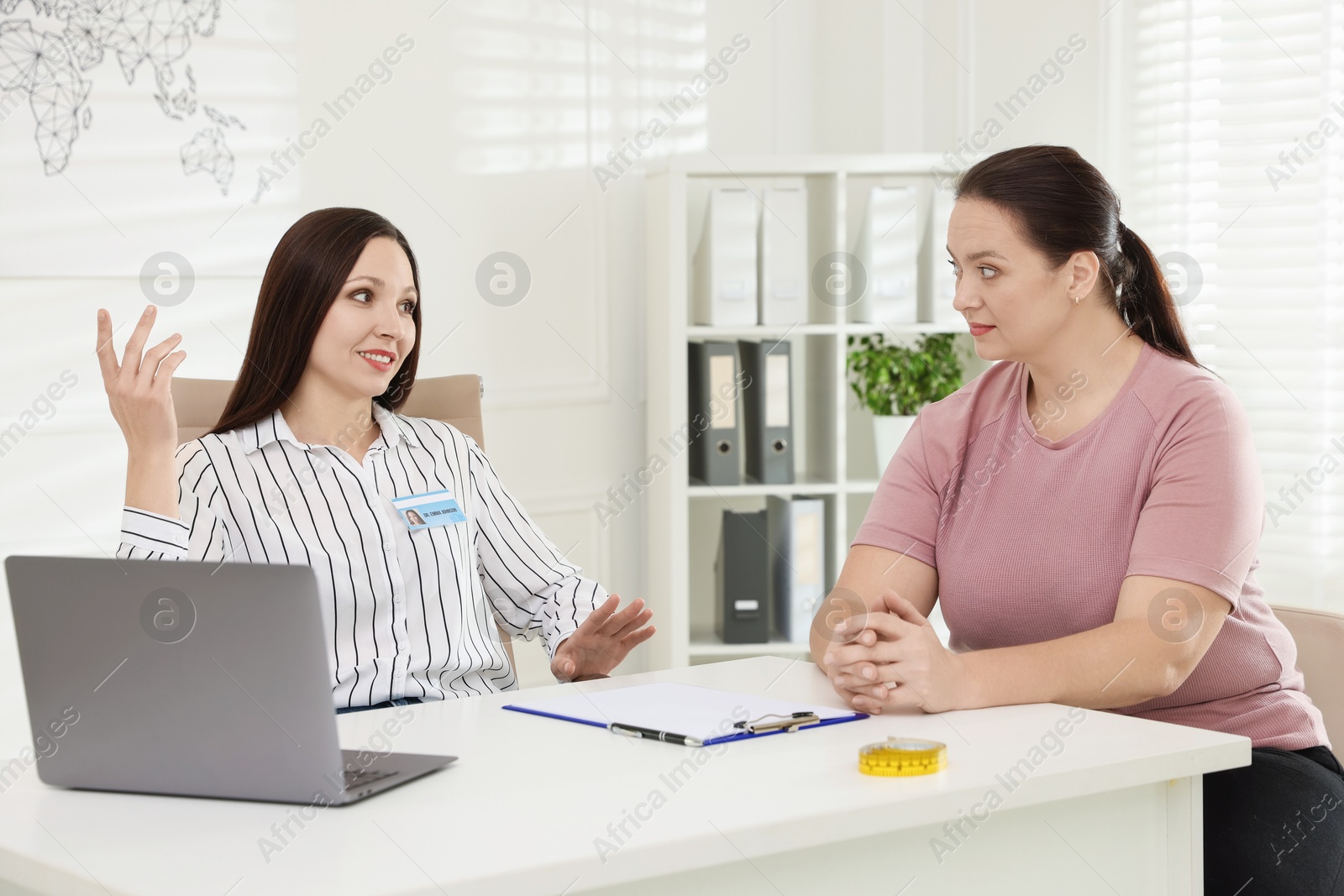 Photo of Overweight woman having consultation with nutritionist at desk in clinic