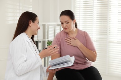 Photo of Nutritionist with notebook giving recommendations to overweight woman in hospital