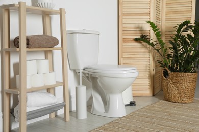 Photo of Folding screen, toilet bowl and houseplant in restroom