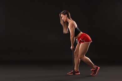 Photo of Woman in gym clothes doing exercise with elastic band on black background