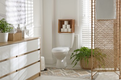 Photo of Folding screen, toilet bowl and houseplants in restroom