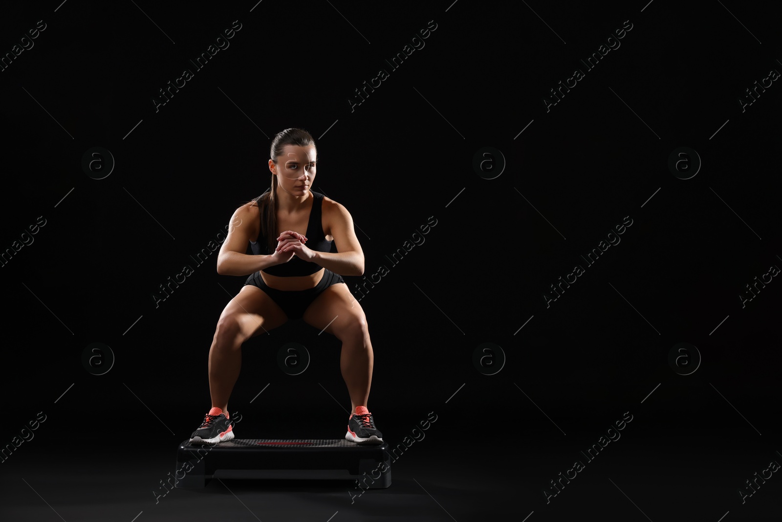 Photo of Beautiful woman in sportswear training on black background. Space for text