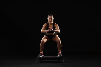 Photo of Beautiful woman in sportswear training on black background