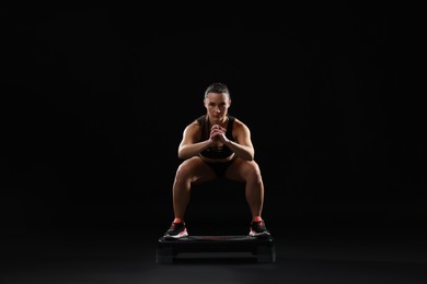 Photo of Beautiful woman in sportswear training on black background