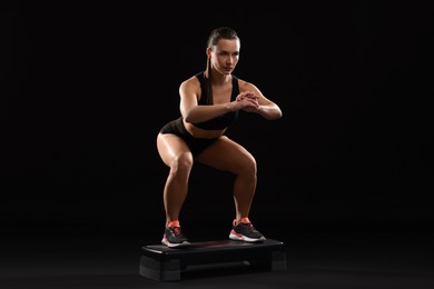 Photo of Beautiful woman in sportswear training on black background