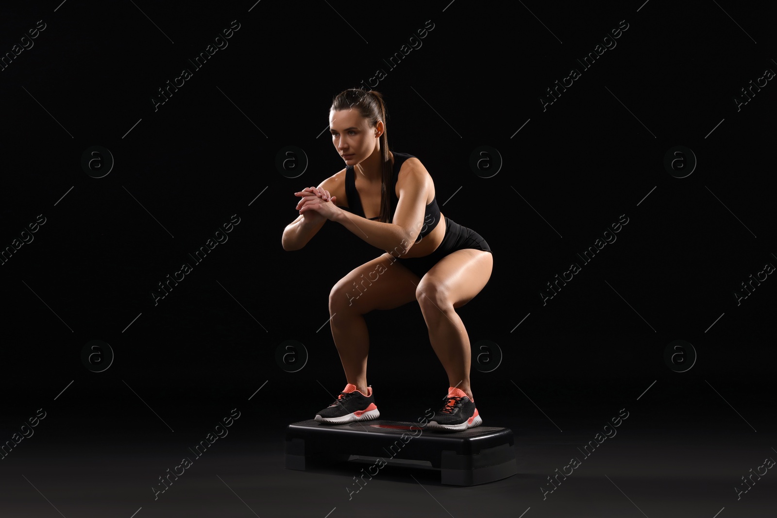 Photo of Beautiful woman in sportswear training on black background