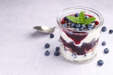 Photo of Tasty trifle dessert. Blueberries, sponge cake and whipped cream in glass on light grey table, space for text