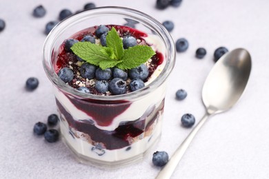 Photo of Tasty trifle dessert. Blueberries, sponge cake and whipped cream in glass on light grey table