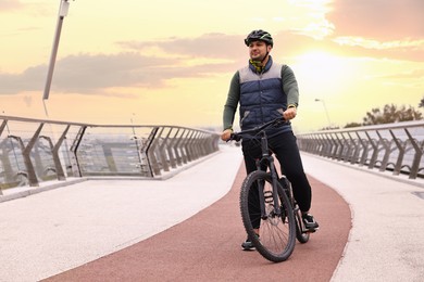 Photo of Man with helmet and bicycle outdoors, space for text