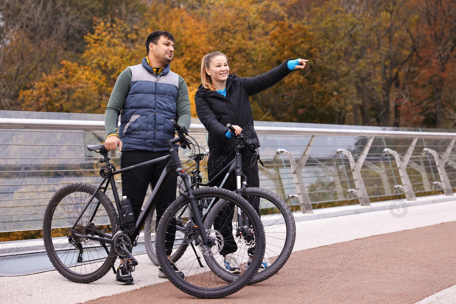 Photo of Beautiful happy couple with bicycles spending time together outdoors, space for text