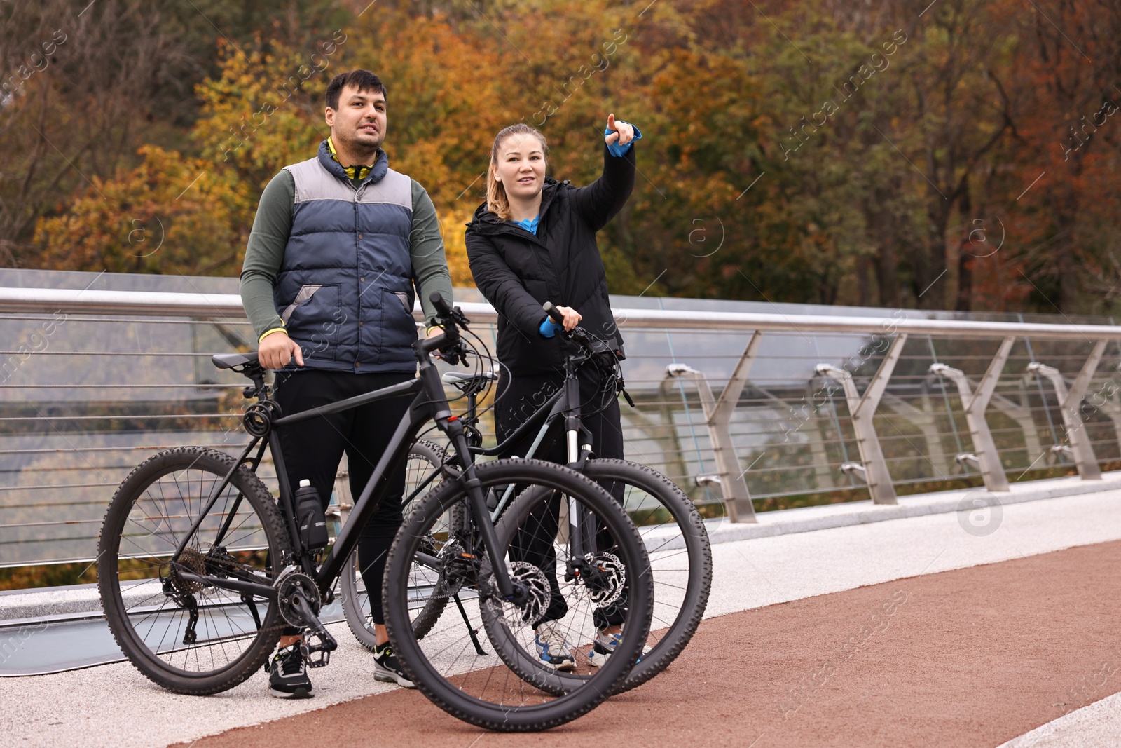 Photo of Beautiful happy couple with bicycles spending time together outdoors, space for text