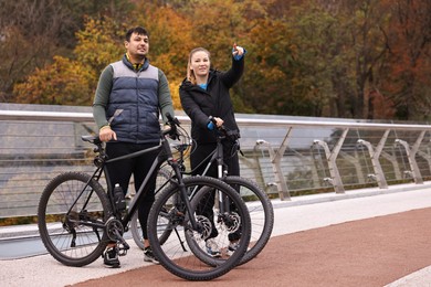 Photo of Beautiful happy couple with bicycles spending time together outdoors, space for text