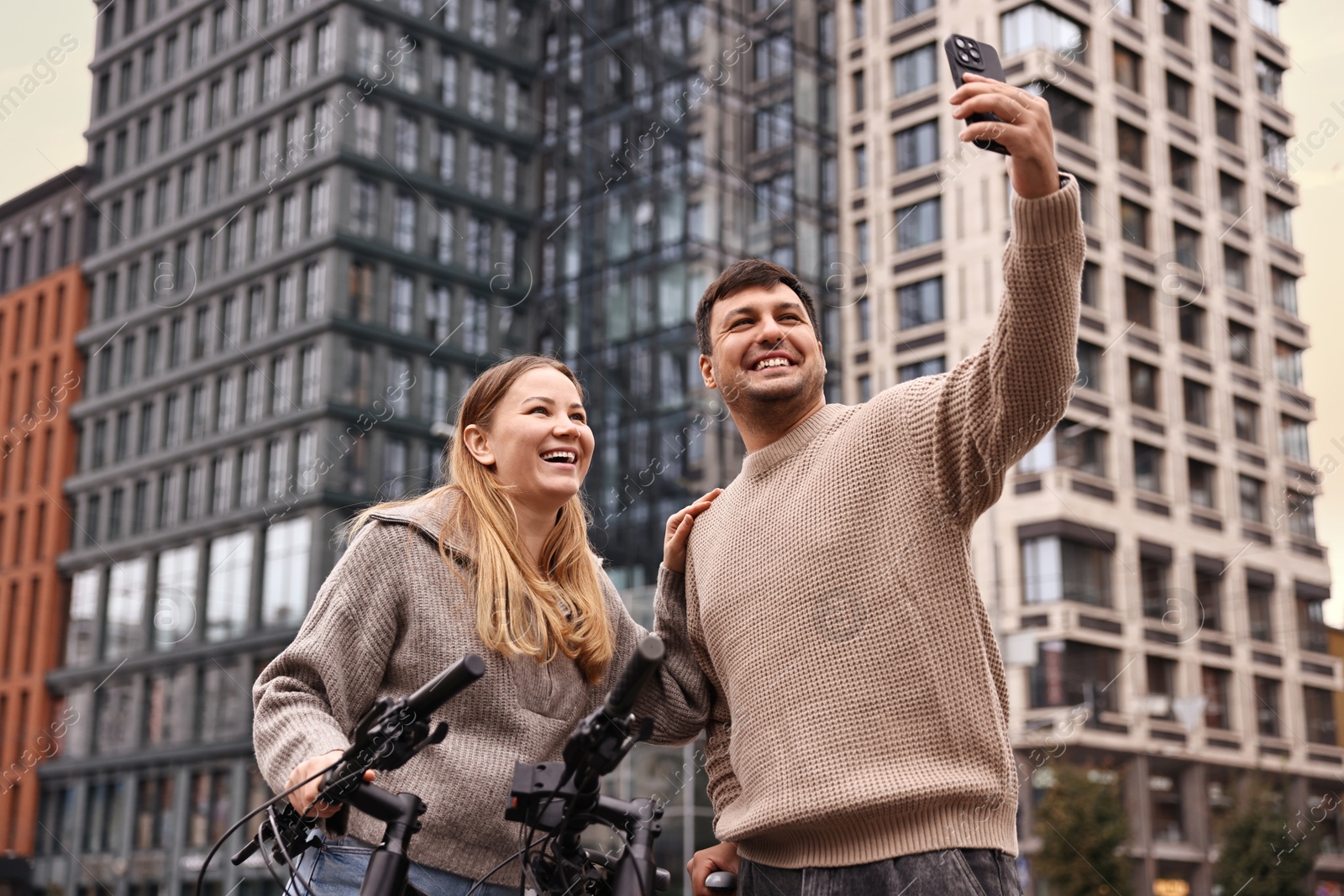 Photo of Beautiful happy couple with bicycles taking selfie outdoors