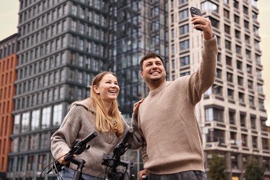 Photo of Beautiful happy couple with bicycles taking selfie outdoors