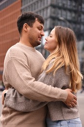 Photo of Beautiful happy couple hugging on city street