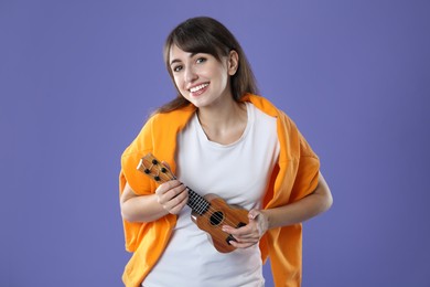 Photo of Happy woman playing ukulele on purple background