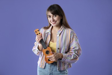 Photo of Happy woman playing ukulele on purple background