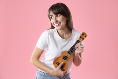 Photo of Happy woman playing ukulele on pink background