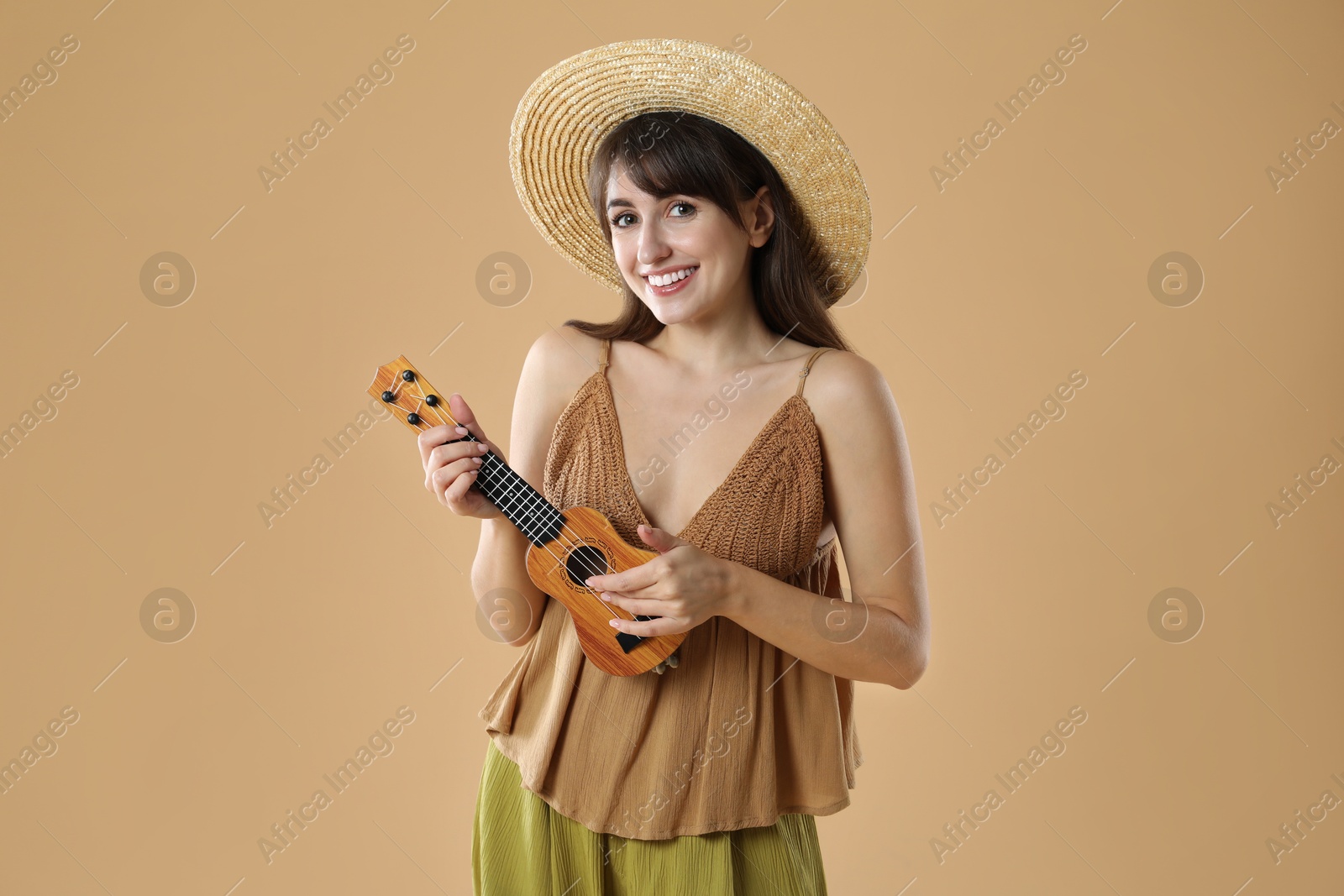 Photo of Happy woman playing ukulele on beige background