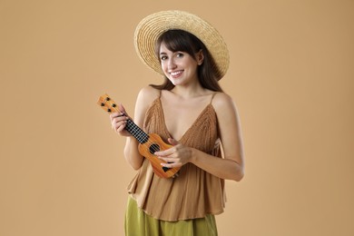 Photo of Happy woman playing ukulele on beige background