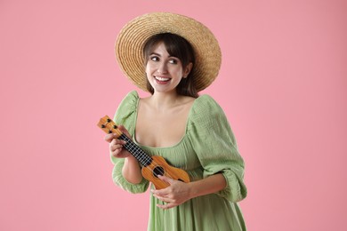 Photo of Happy woman playing ukulele on pink background