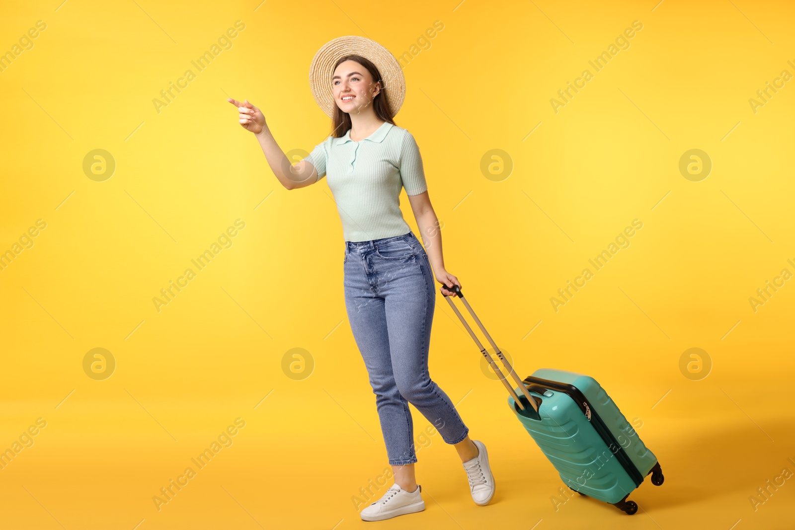 Photo of Woman in straw hat with suitcase on orange background