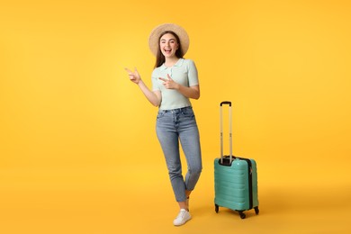 Photo of Woman in straw hat with suitcase on orange background