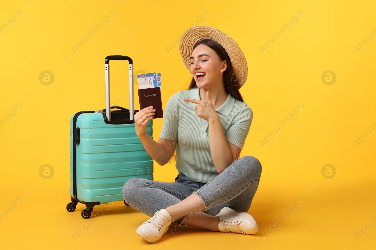 Photo of Woman with tickets, passport and suitcase on orange background