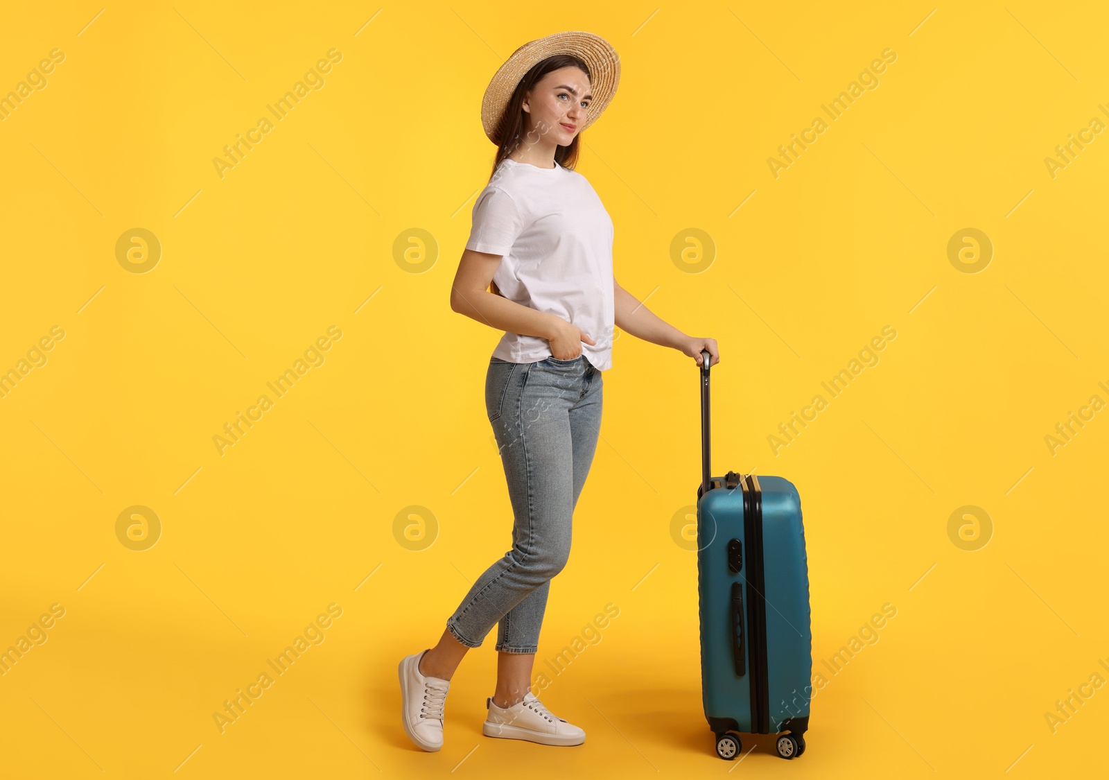 Photo of Woman in straw hat with suitcase on orange background