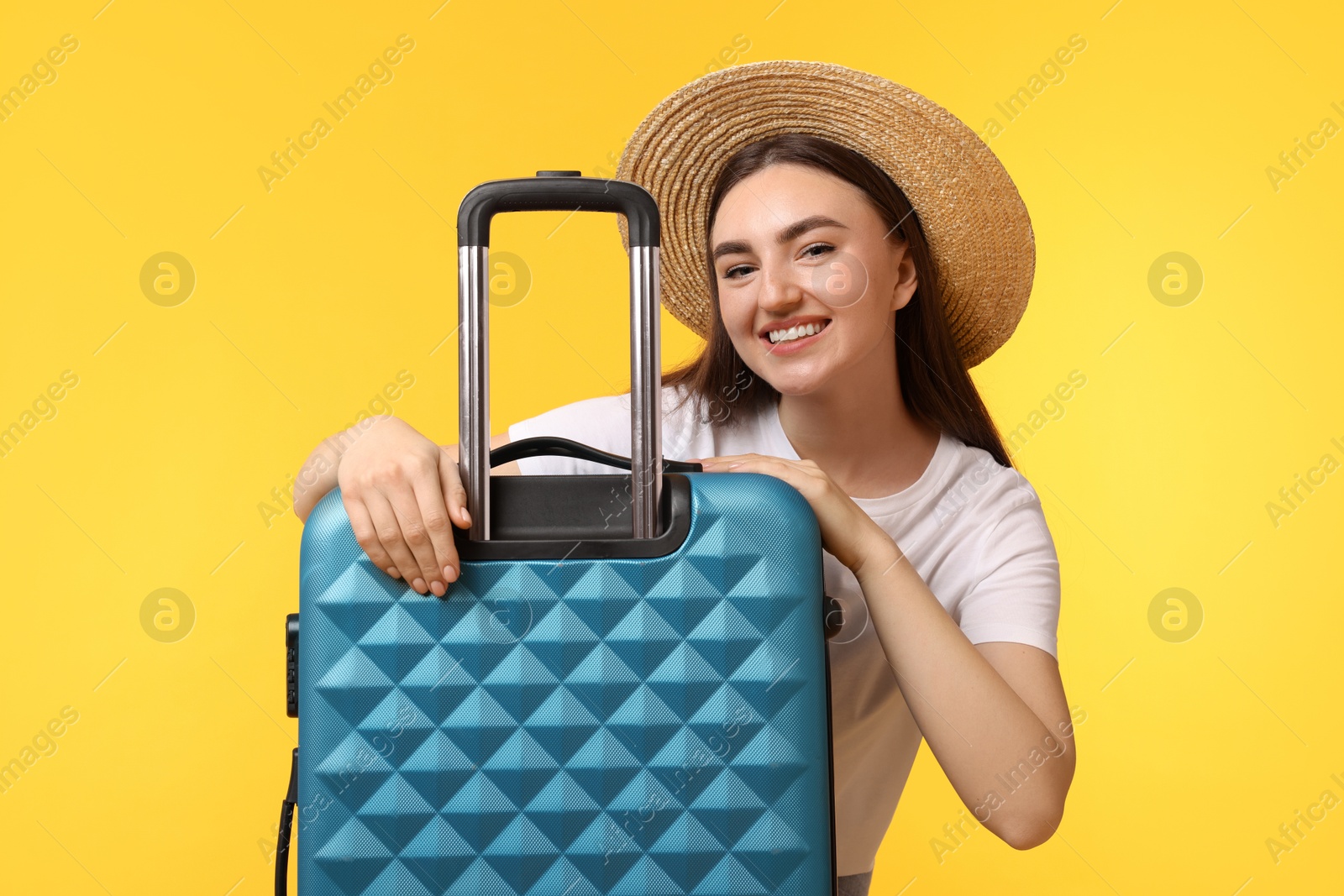 Photo of Woman in straw hat with suitcase on orange background