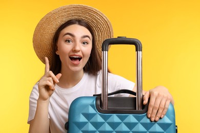 Photo of Woman in straw hat with suitcase on orange background