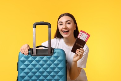 Photo of Woman with tickets, passport and suitcase on orange background